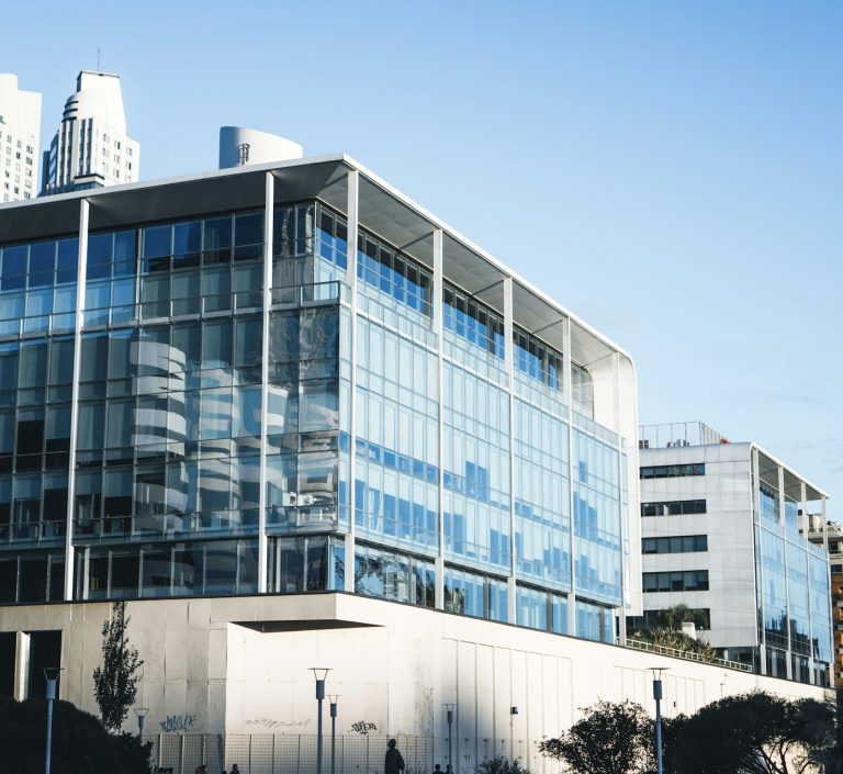 Modernes Gebäude mit Glasfassade vor einem klaren blauen Himmel.